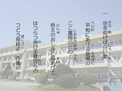 一　空を仰げば白い雲　　　　        平和にあける故郷の 　　ここ富岡の丘の上　　　　        自主のおしえに眉あげて 　　はつらつ伸びる健児らの　        つどう母校よ　西富小